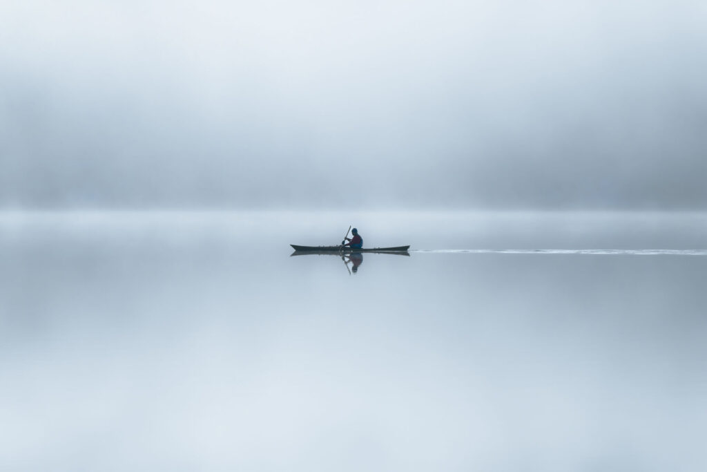 Sous une brune épaisse, miroitant au fil de l'eau, j'observe ce kayakiste exercer sa passion quotidienne sur le Lac Bohinj dans les Alpes Juliennes.