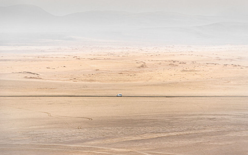 Le vent balaye le chemin de sable chaud, le désert nous murmure un chant libertaire des grands espaces et le soleil illumine la toile grise de l’horizon.